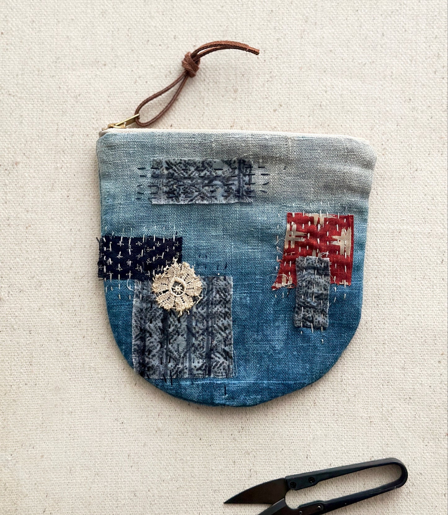 Indigo-dyed round zip pouch in Japanese Boro style with patchwork fabrics with sashiko stitching
